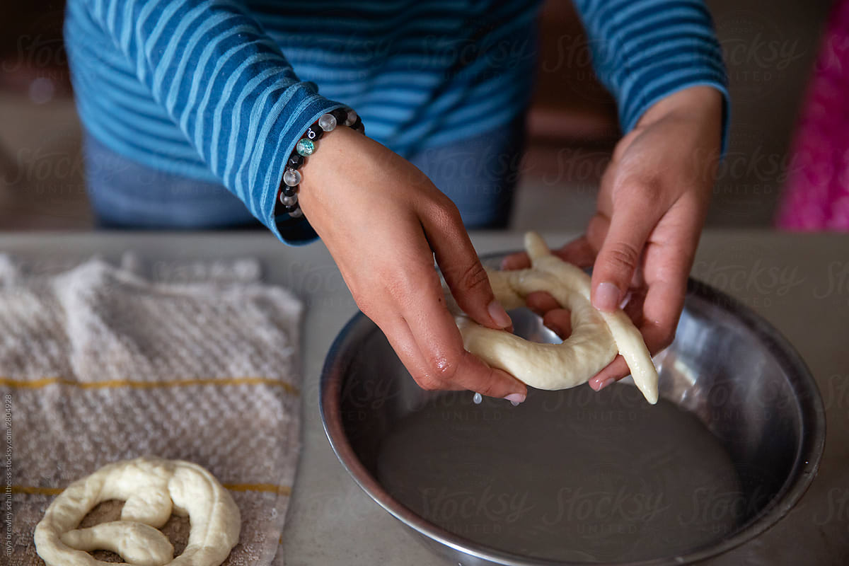A pair of hands dipping dough into prepared water