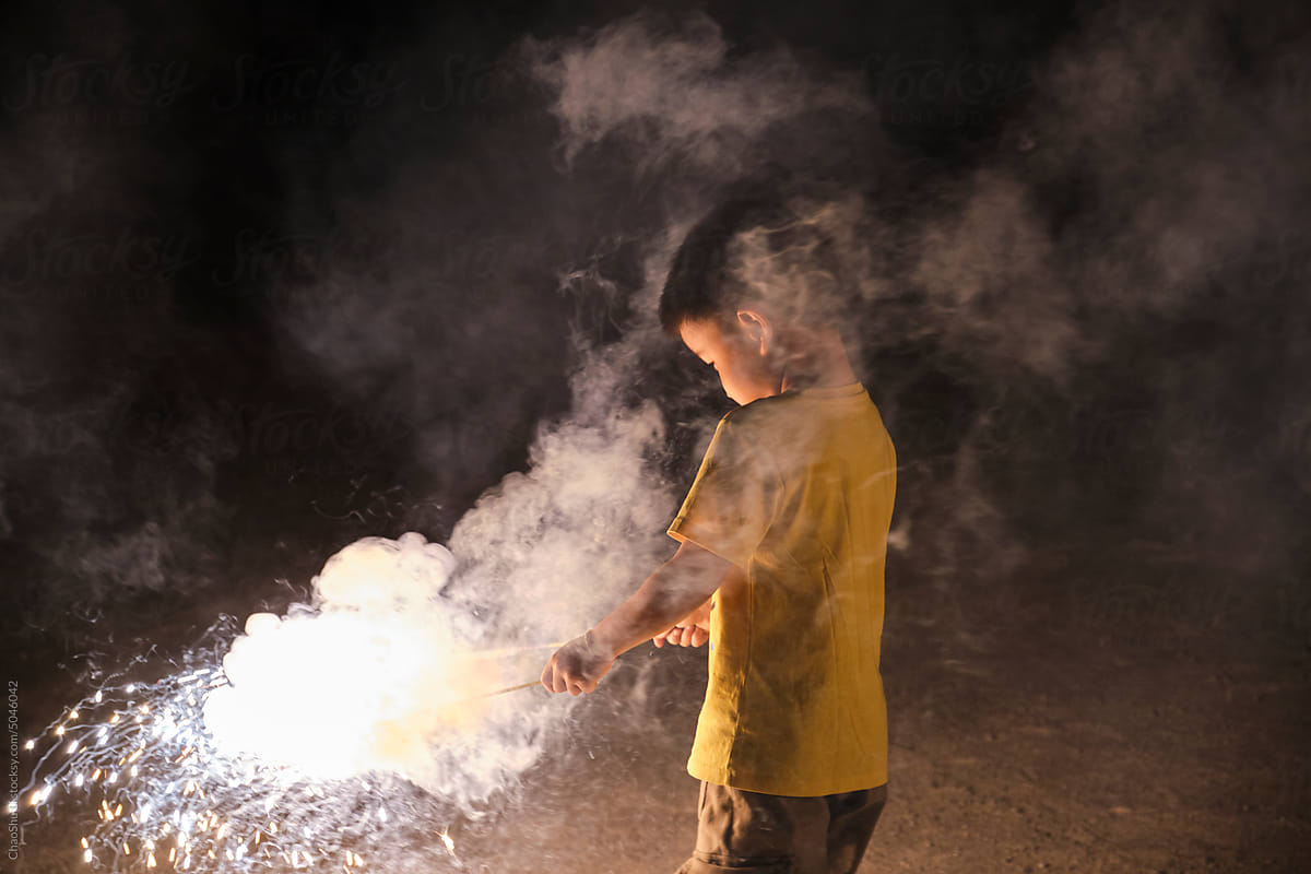 Asian little boy, playing with firework at night in nature outdoors