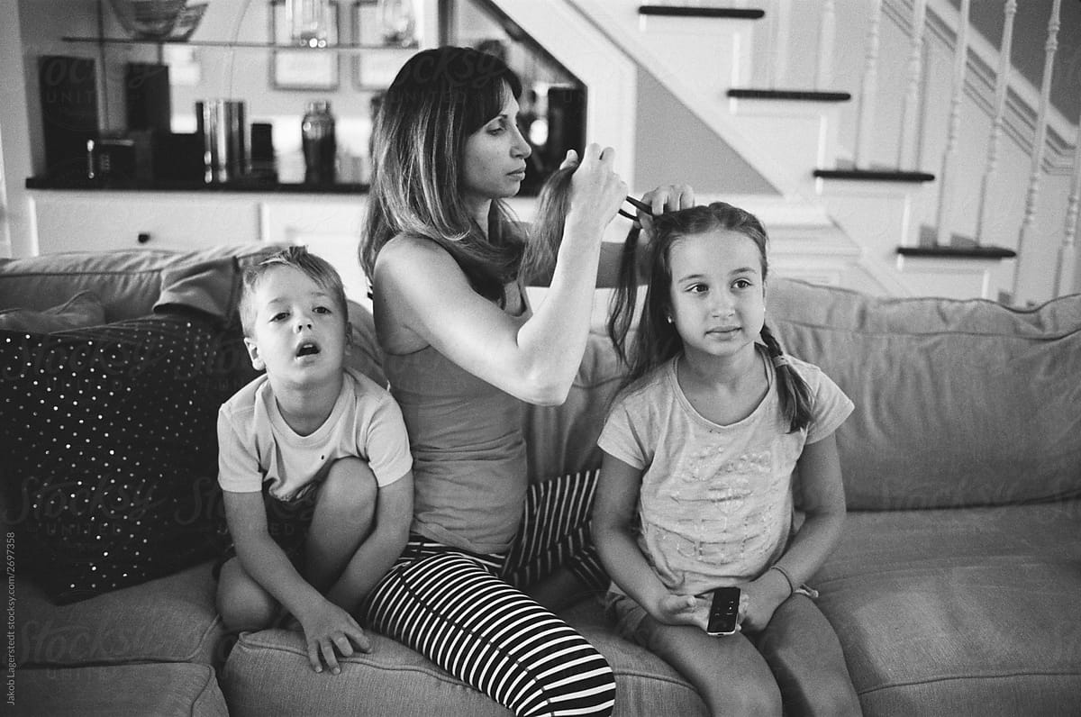 Mother Doing Daughters Hair While Brother And Sister Are Watching