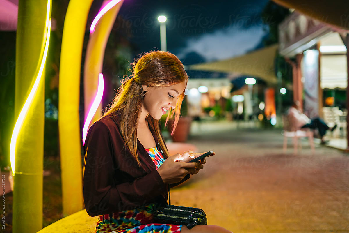 Cuban woman texting on cellphone at night