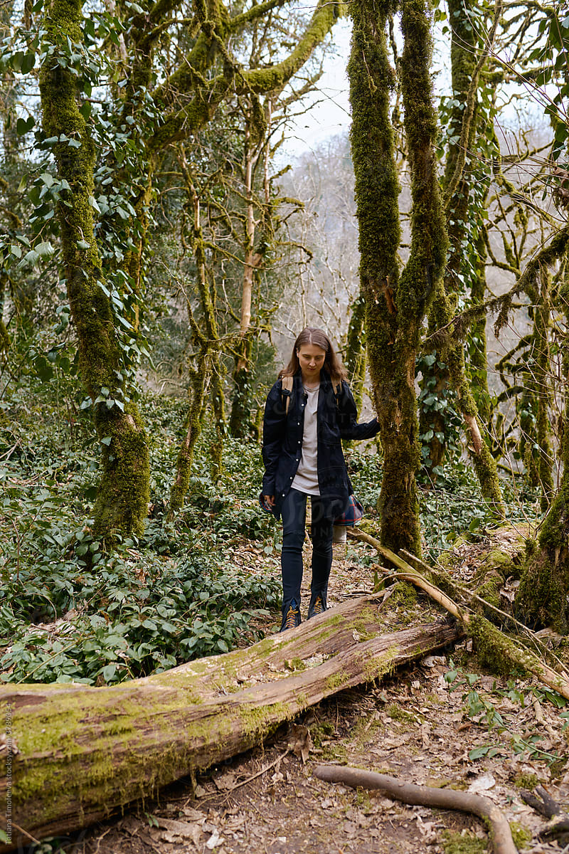 young woman travels through an old dead forest with a backpack