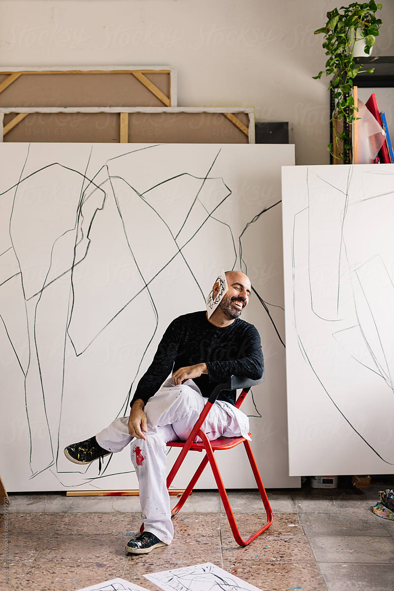 portrait of an artist in his studio. He sits in a red chair