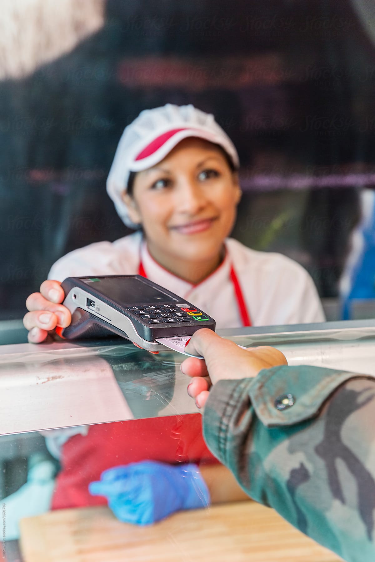 A woman paying a bill with a credit card on a butcher shop