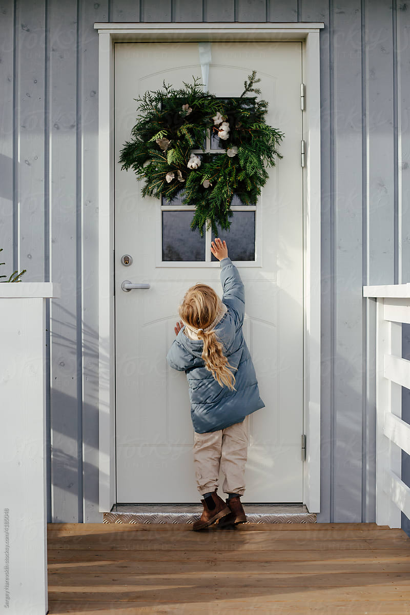 Girl touching wreath hanging on door