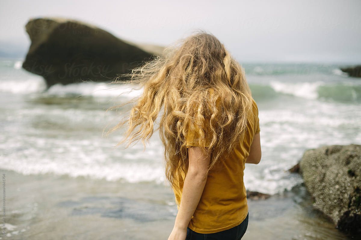 Woman with long brown hair blowing in the wind on a beach in Oregon