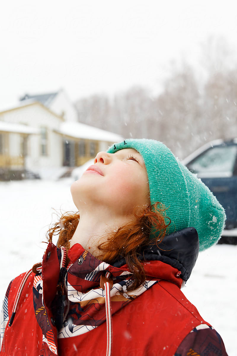 Redhead girl enjoying snowfall in countryside
