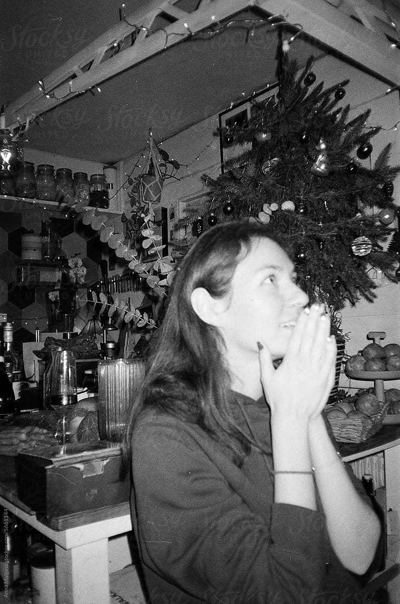 a woman wishing a desire under a christmas tree