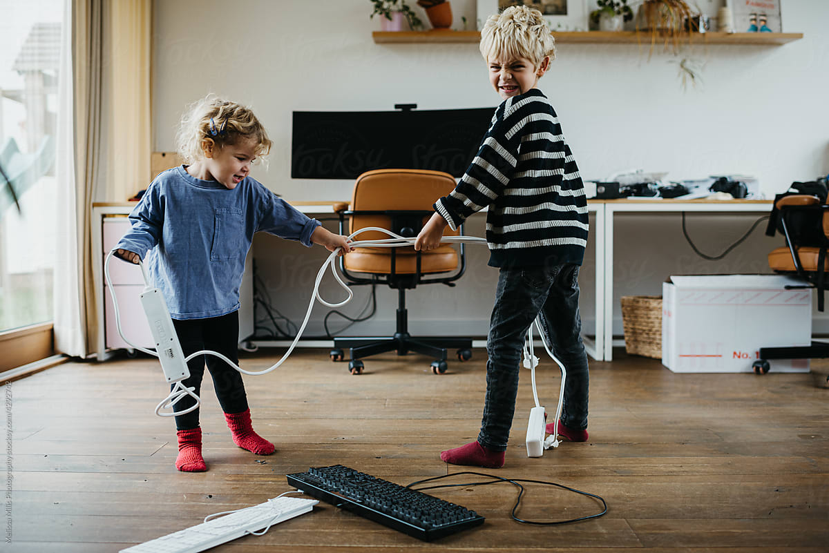 Two little children playing with wires and cables
