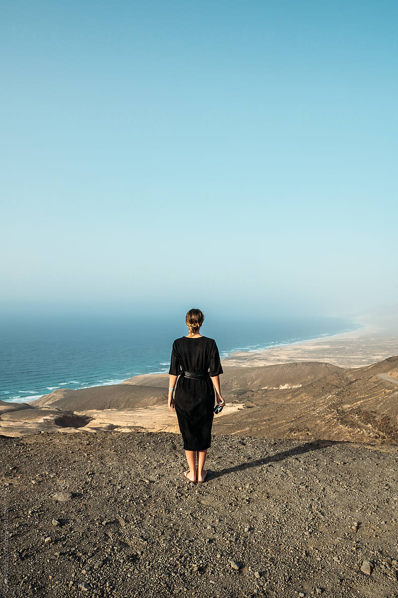Woman standing on hill near sea