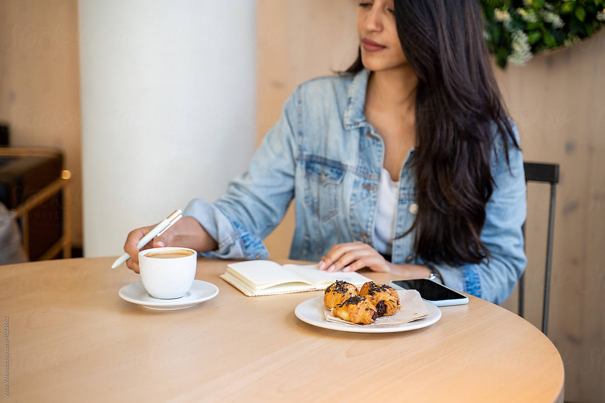 Young woman writing notes while coffe break