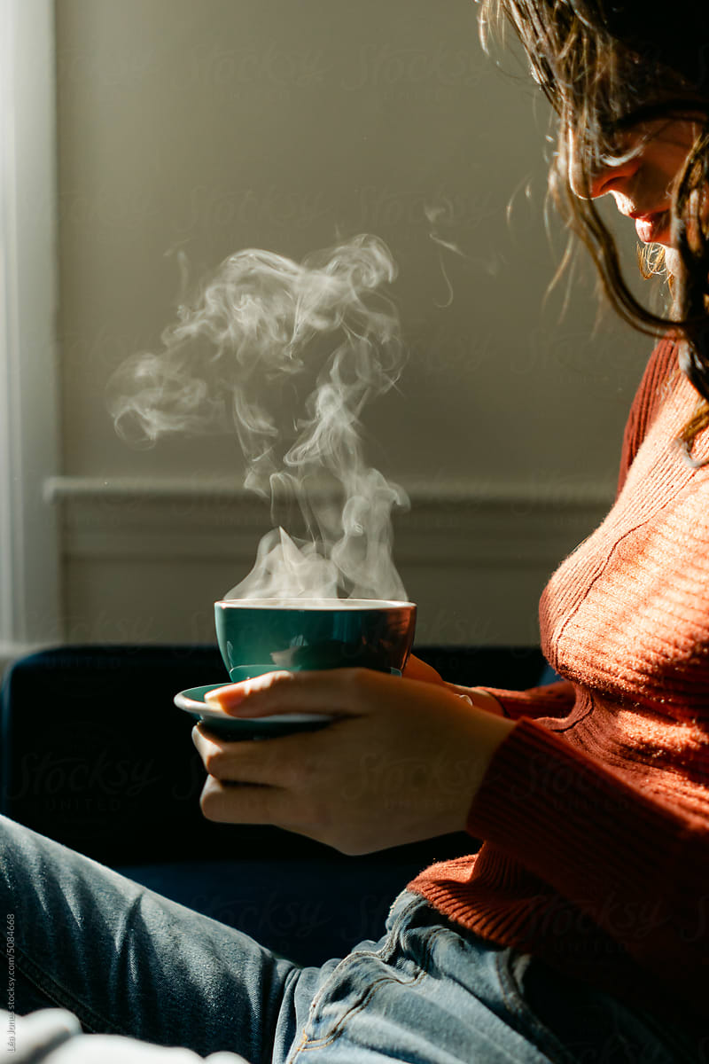 woman with steaming cup in sunlight