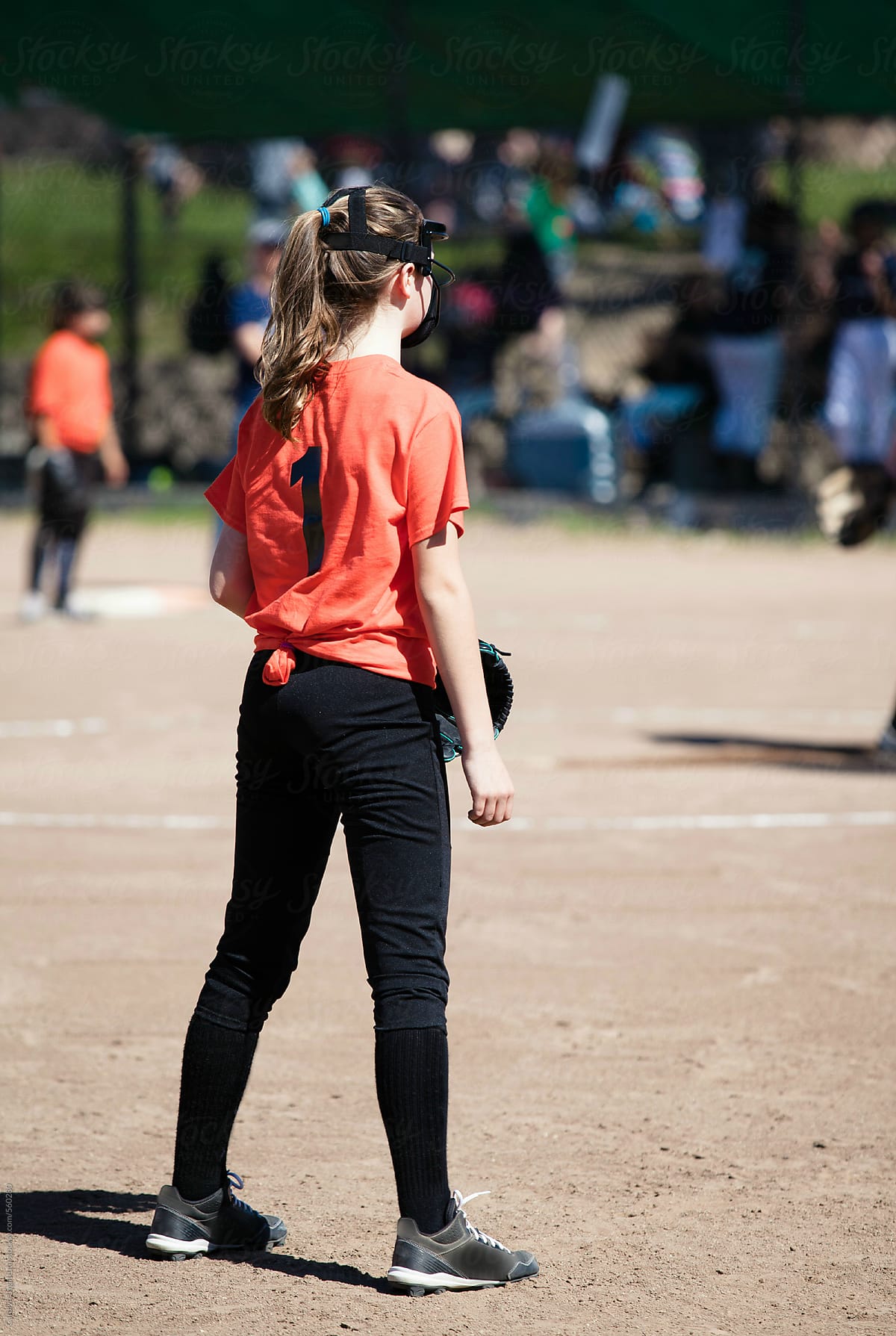 Teenage girl in a softball game wearing protective head gear