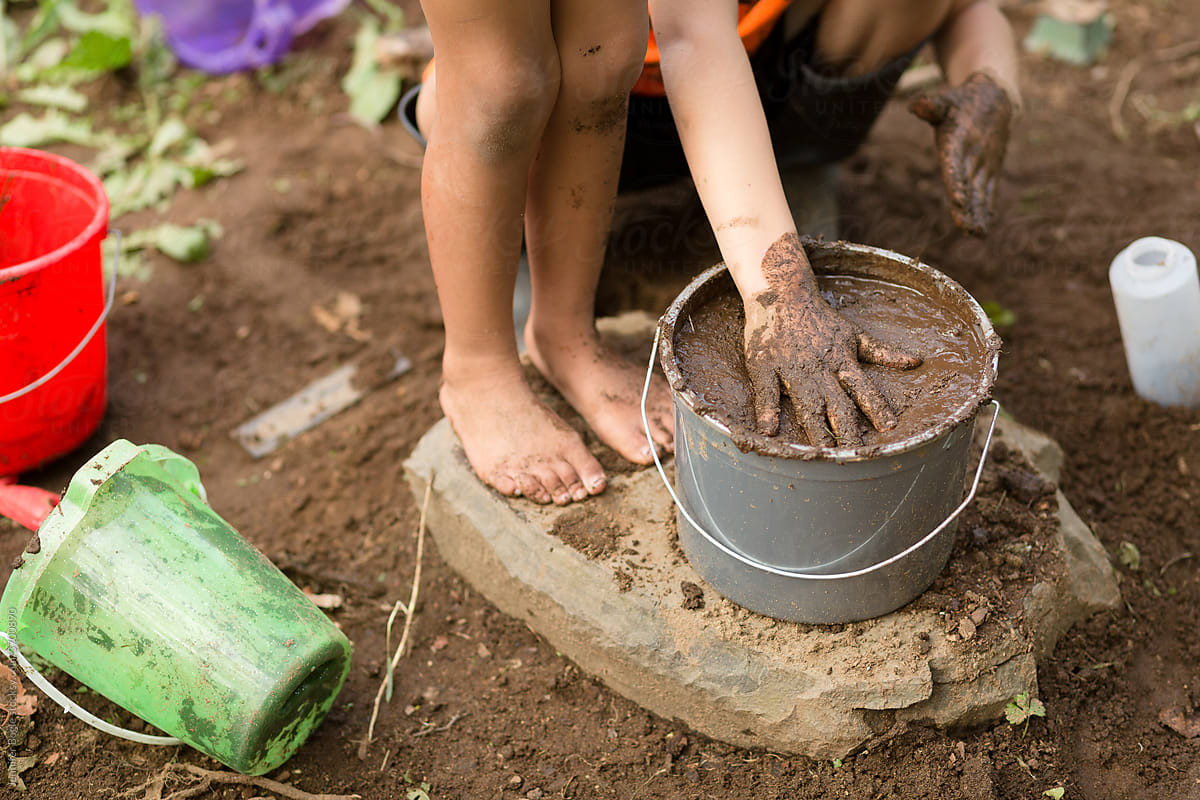 Faceless children playing with mud pit