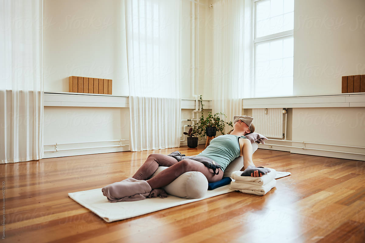 Woman doing restorative yoga using bolsters