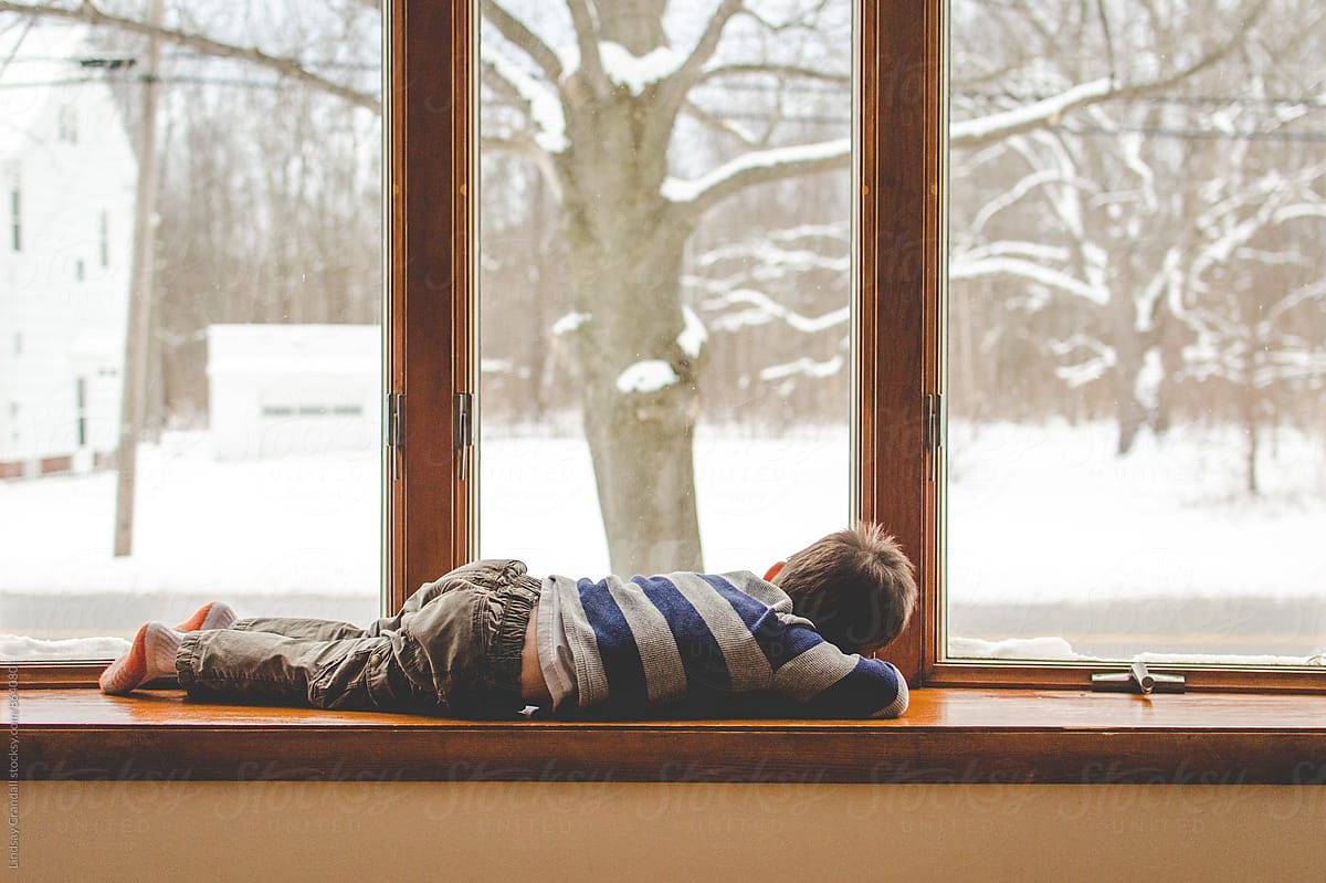 Boy lying beside a snowy window