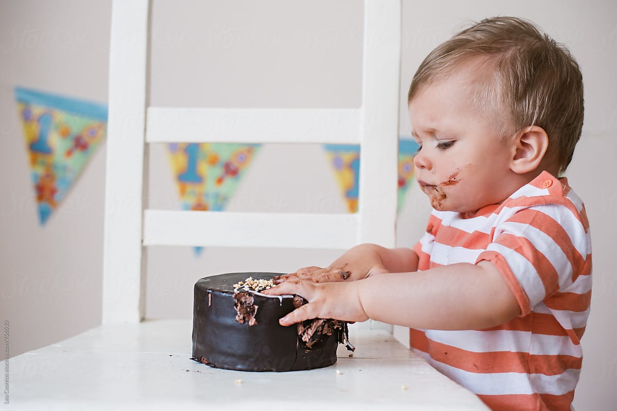 Portrait of a little boy just starting to smash his birthday cake