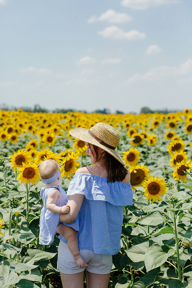 Woman with baby in field of sunflowers