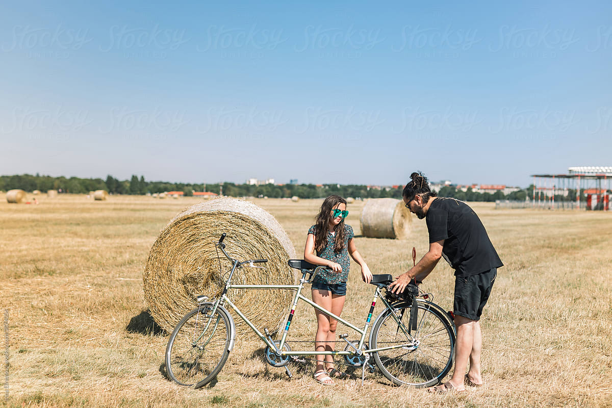 Father and daughter with a tandem bike on the field