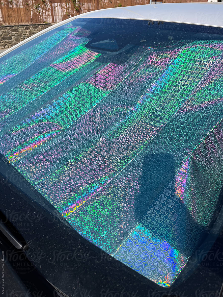 Car windscreen sun visor of metallic colors with a shadow of a hand