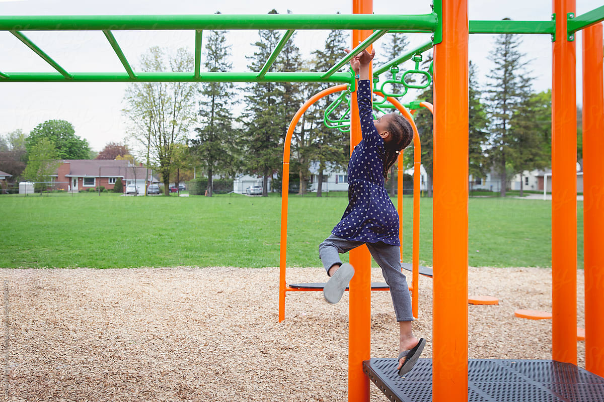 Young girl jumping onto the monkey bars at a playground