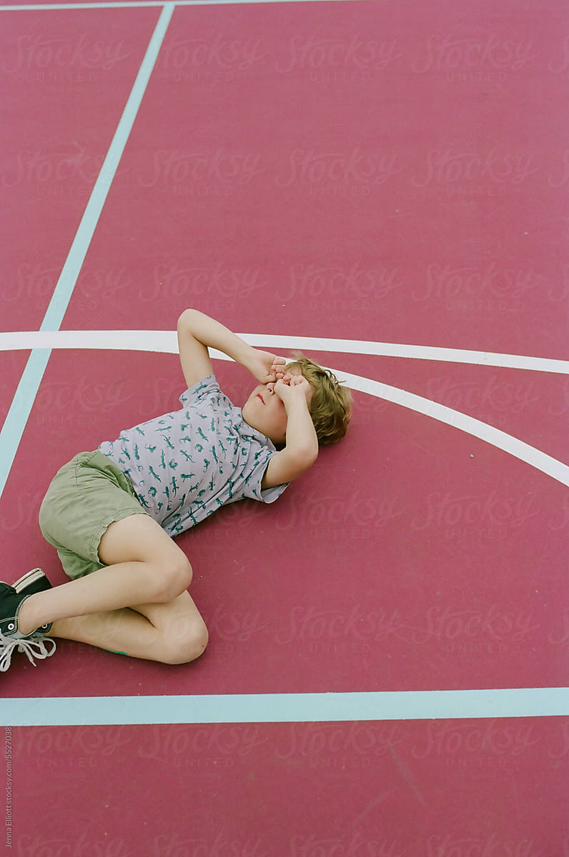 Boy Lies on the Ground Covering His Eyes