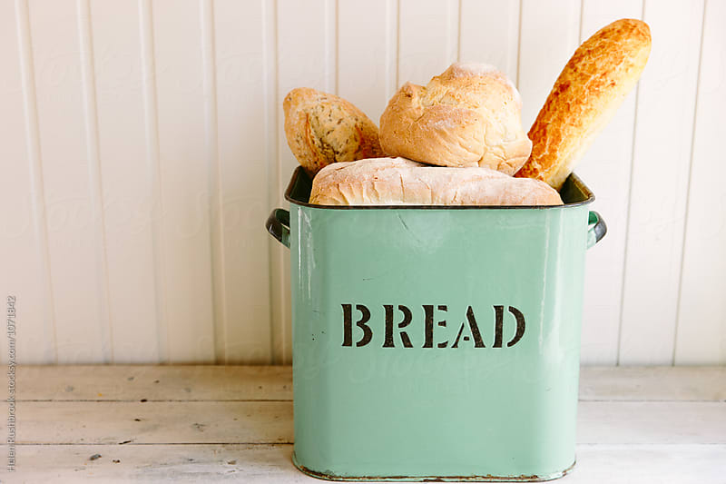 Various types of bread in a vintage bread bin.