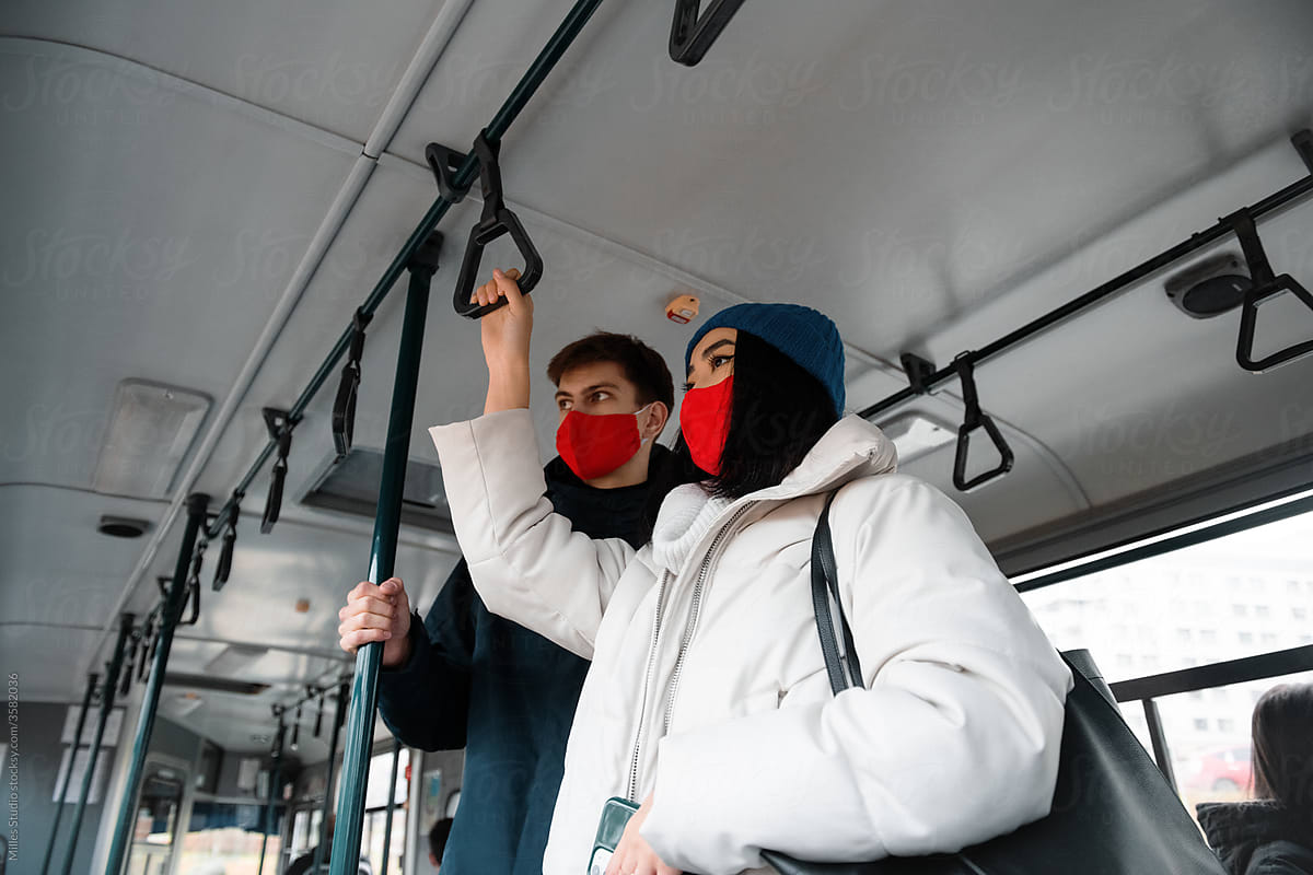 Multiracial friends in masks riding modern bus together
