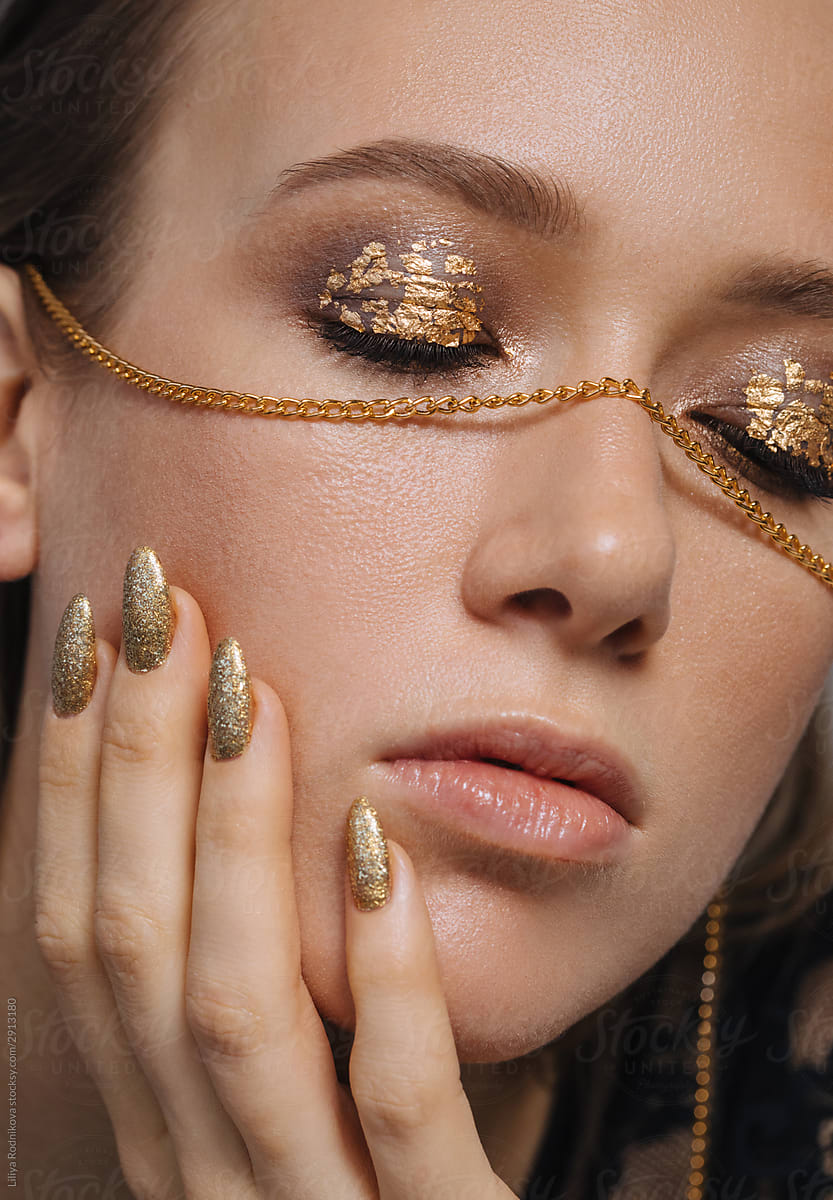 Beautiful woman with golden makeup and manicure