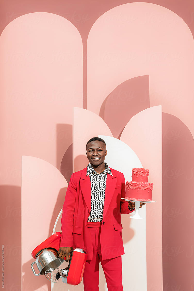 Portrait of a fashionable guy with a cake and a mixer in his hands