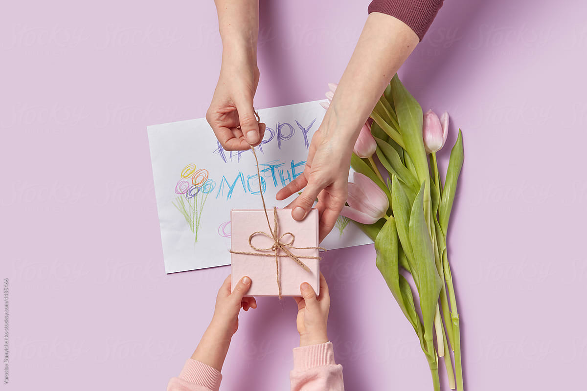 Daughter giving mom tulips, gift box and greeting card