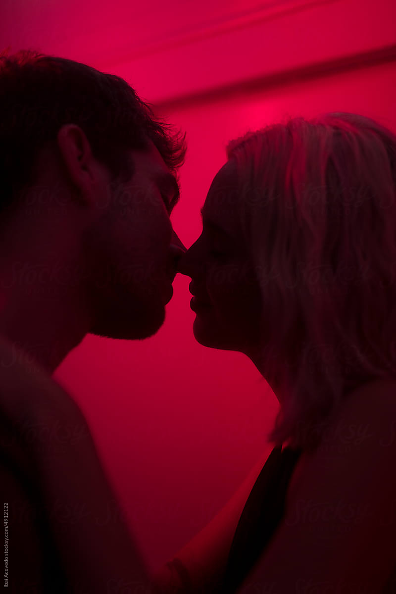Lovers silhouette tenderly kissing with red light