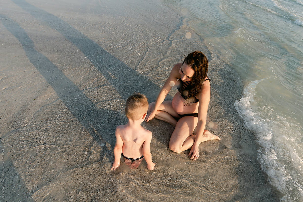 Pregnant mom plays in sand with son