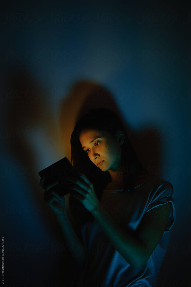 Young woman lit with tablet screen light
