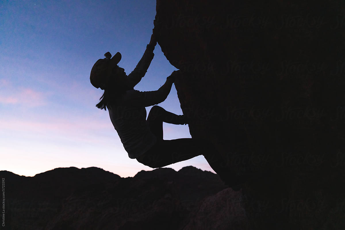 Silhouette of woman bouldering at sunset