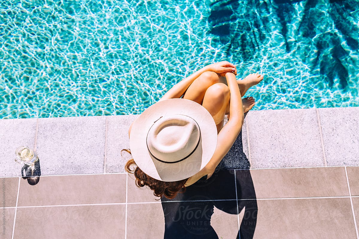 Overhead Shot Of Young Redhead Woman With Hat By The Pool by