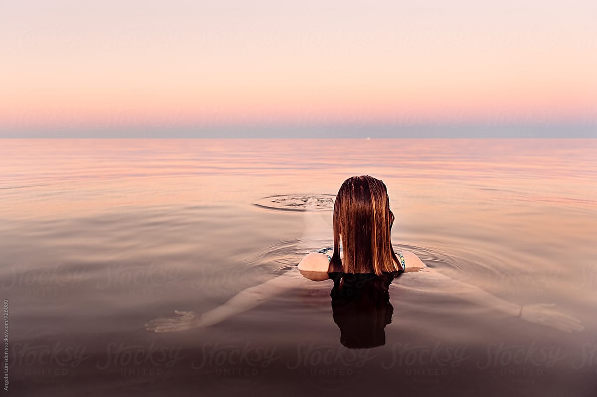 Girl In Shallow Calm Water Relaxes At Dusk Porangela Lumsden