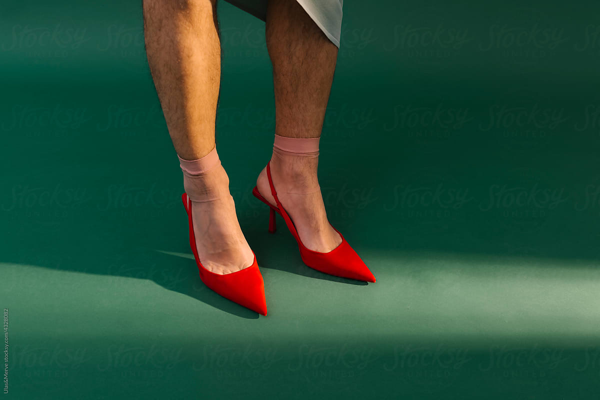 man with red high heels on green background