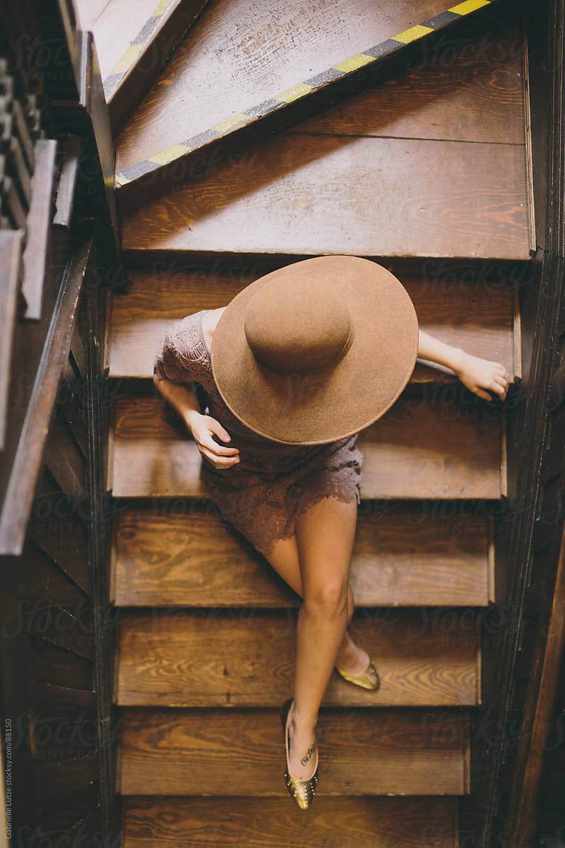 Girl sitting on wood stairs in wide brim hat