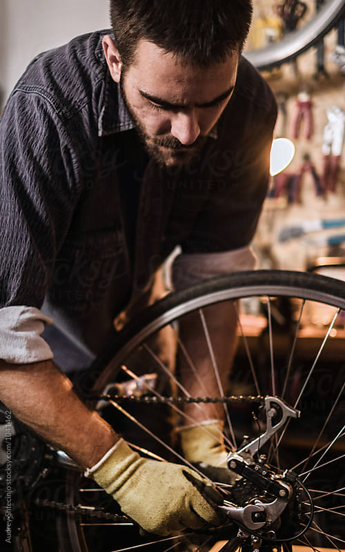Young mechanic working on bike maintenance in his rustic workshop.