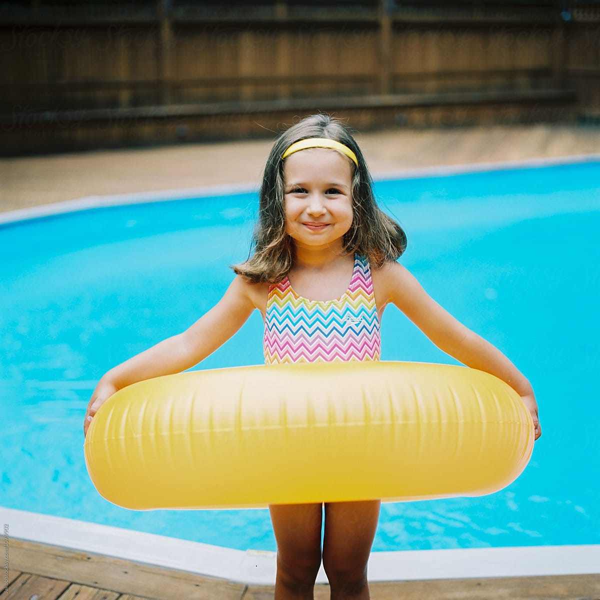 Cute Young Girl With A Big Inner Tube Standing By A Swimming Pool By