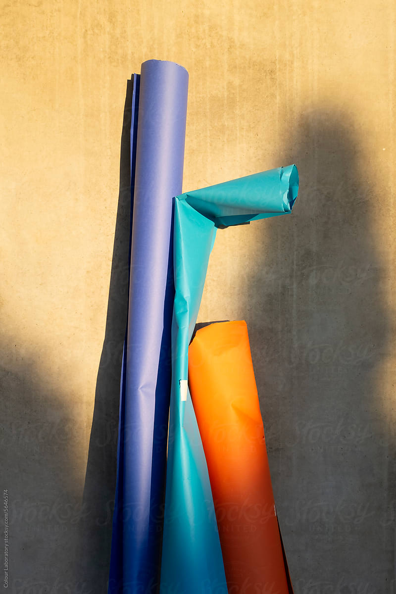Colourful paper rolls leaning on concrete wall & golden hour sunlight
