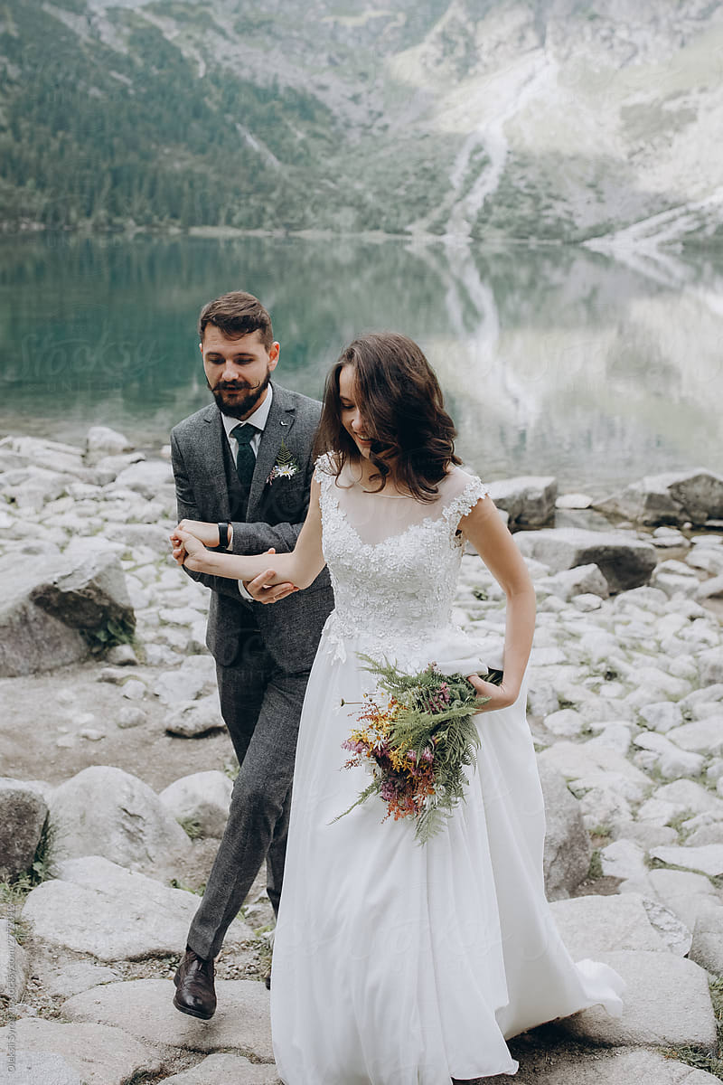 Young married couple walking around lake.