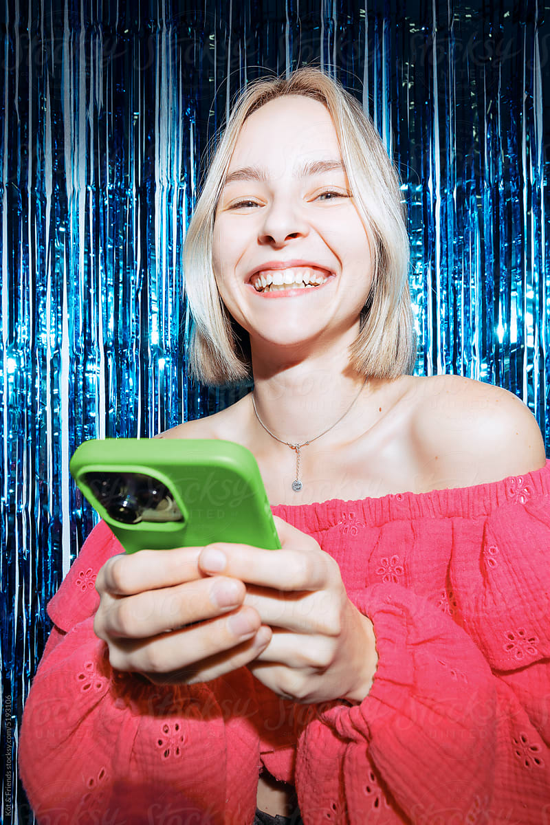 Young Woman With Green Phone Smiling At Party