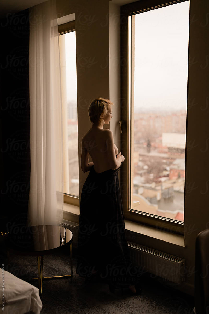 Topless young woman near the window