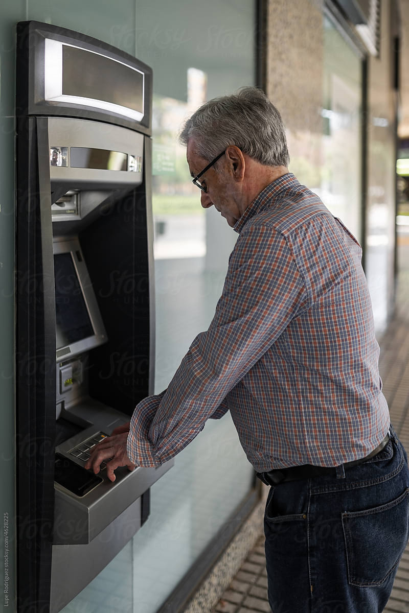 senior man at an ATM withdrawing cash