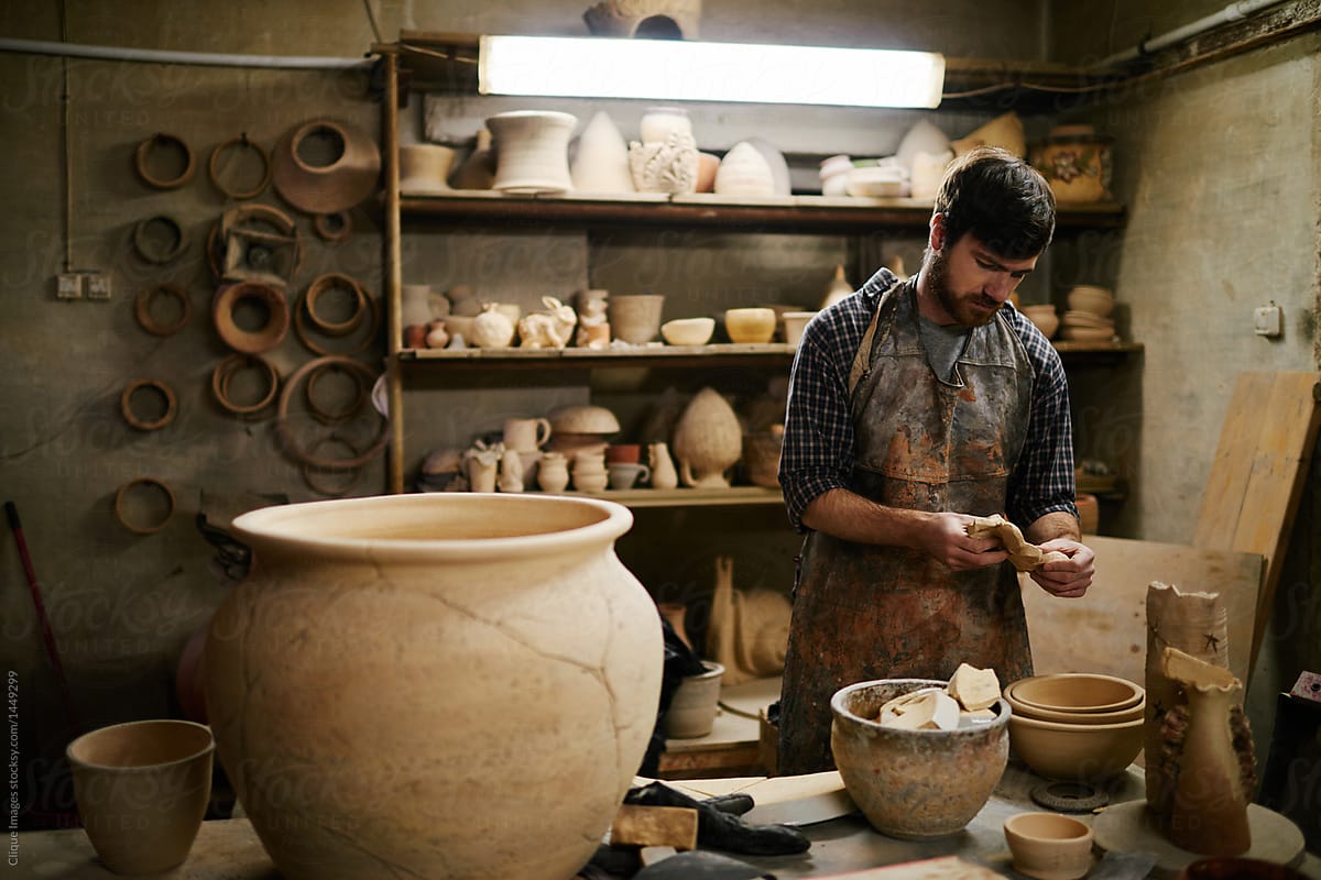 Talented artisan looking at beautiful ceramics on work table in
