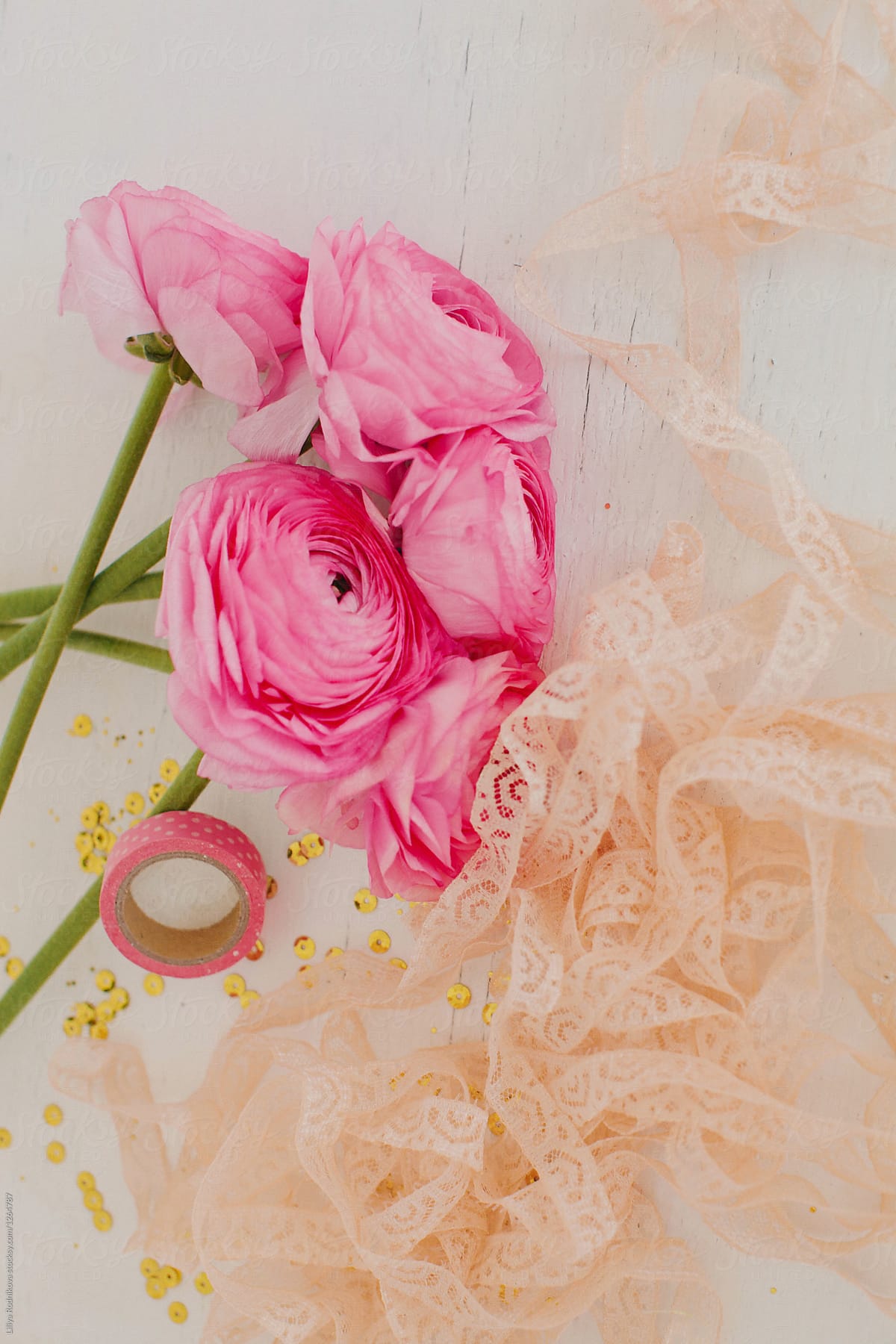 Bouquet of pink ranunculuses and peachy lace on white table
