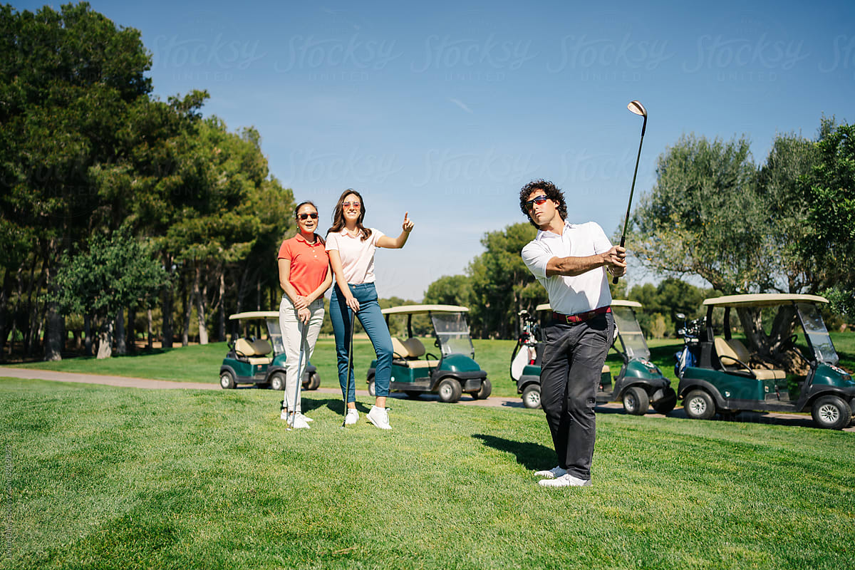 Man playing golf near women