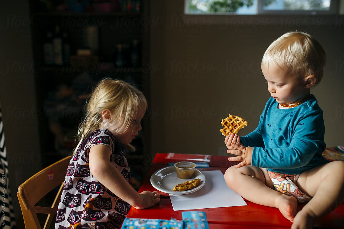 Young girl and her baby brother share a snack
