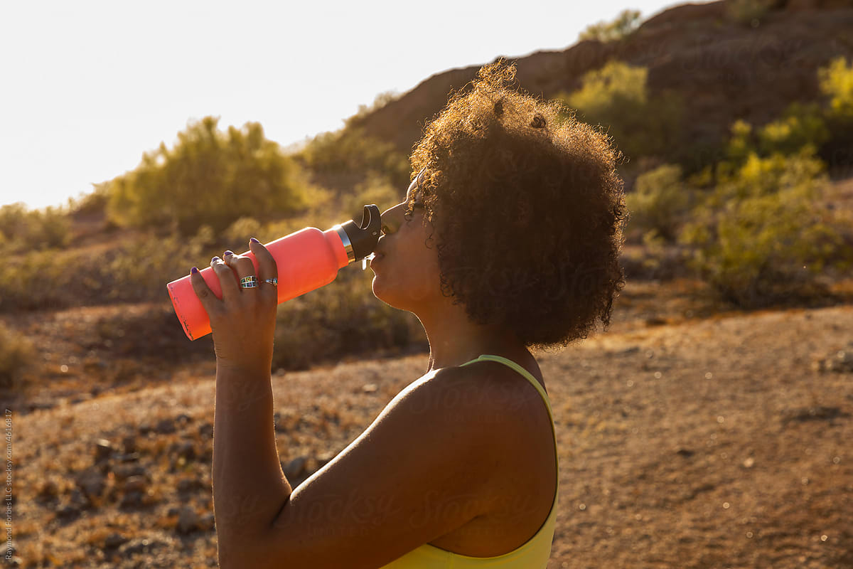 Portrait  Happy Smiling black girl drinking from Water bottle on hike